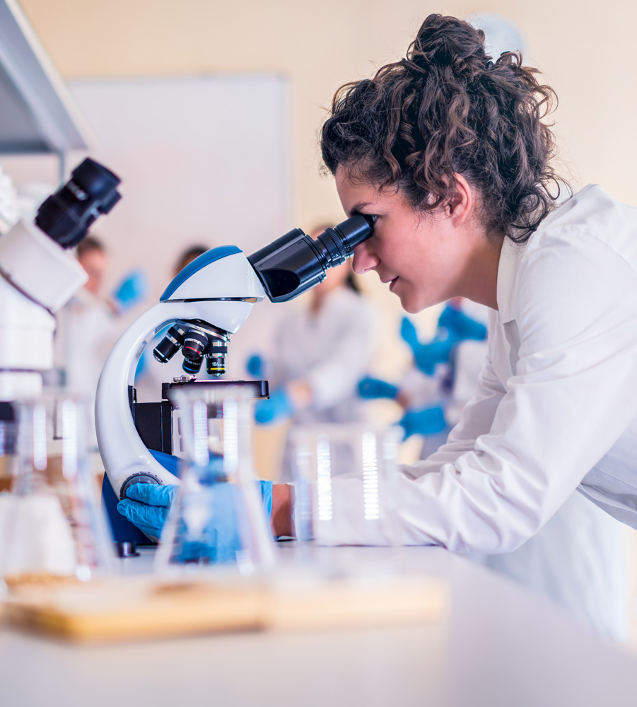 Medical professional looking through microscope at tissue.